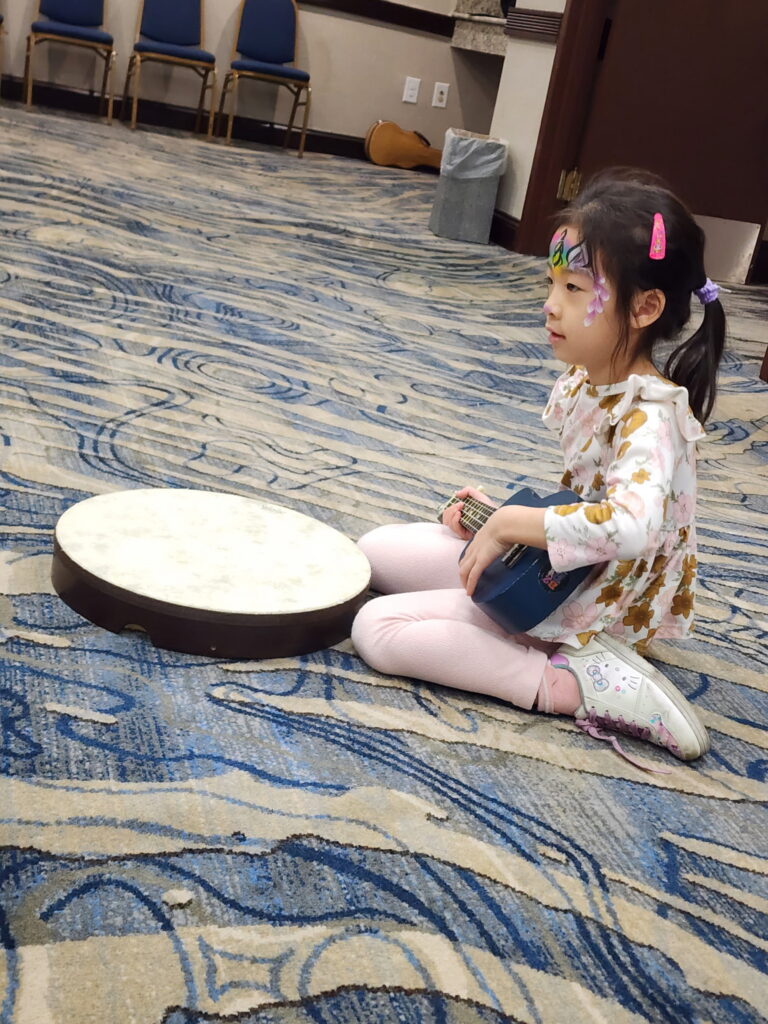 Girl sits on the floor with two instruments