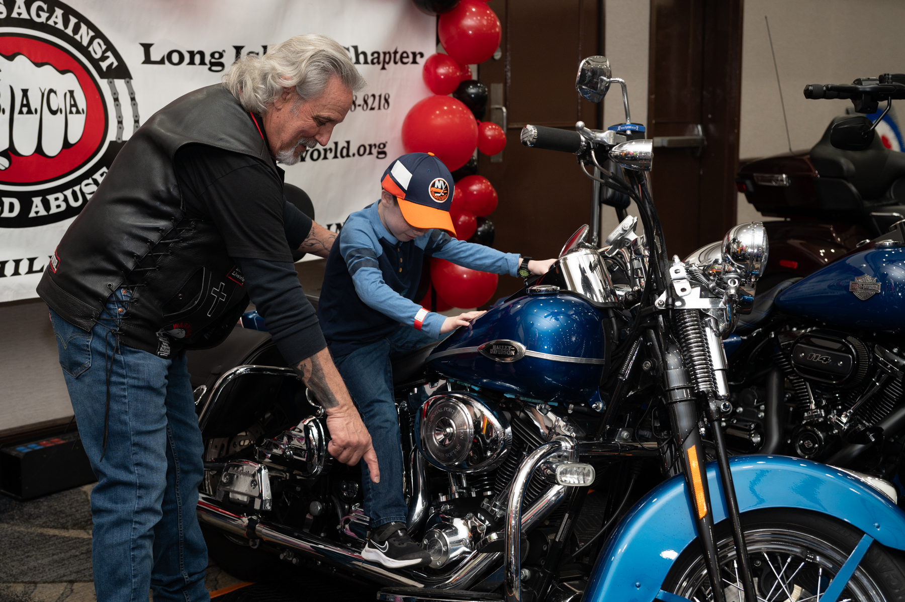 A biker helps a boy onto a motorcycle